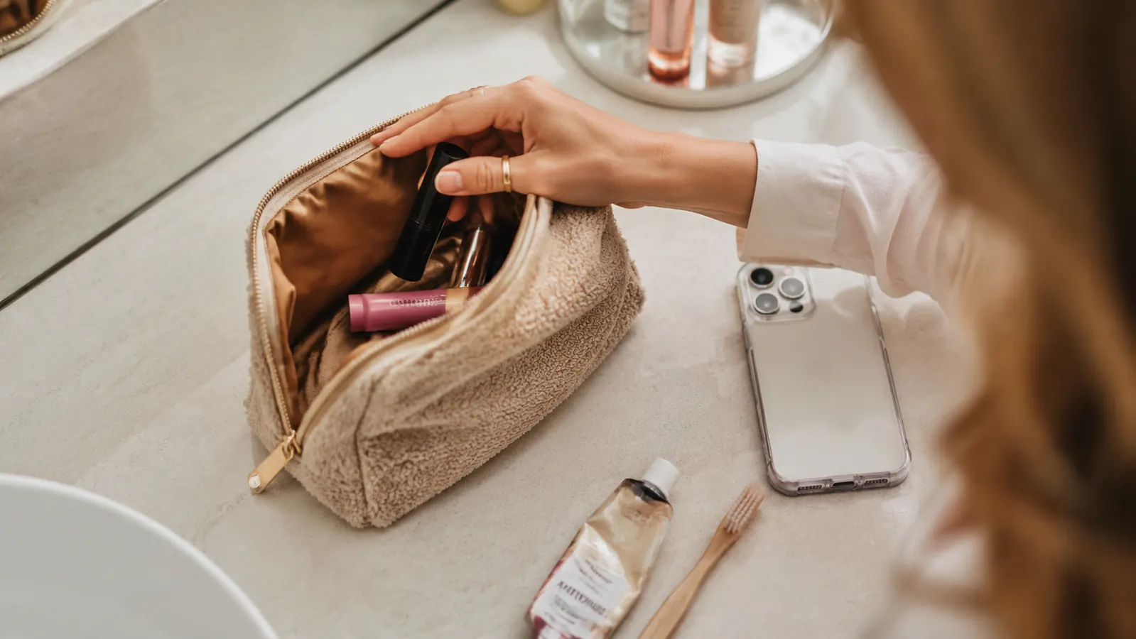Open makeup bag with a drugstore mascara tucked next to everyday essentials