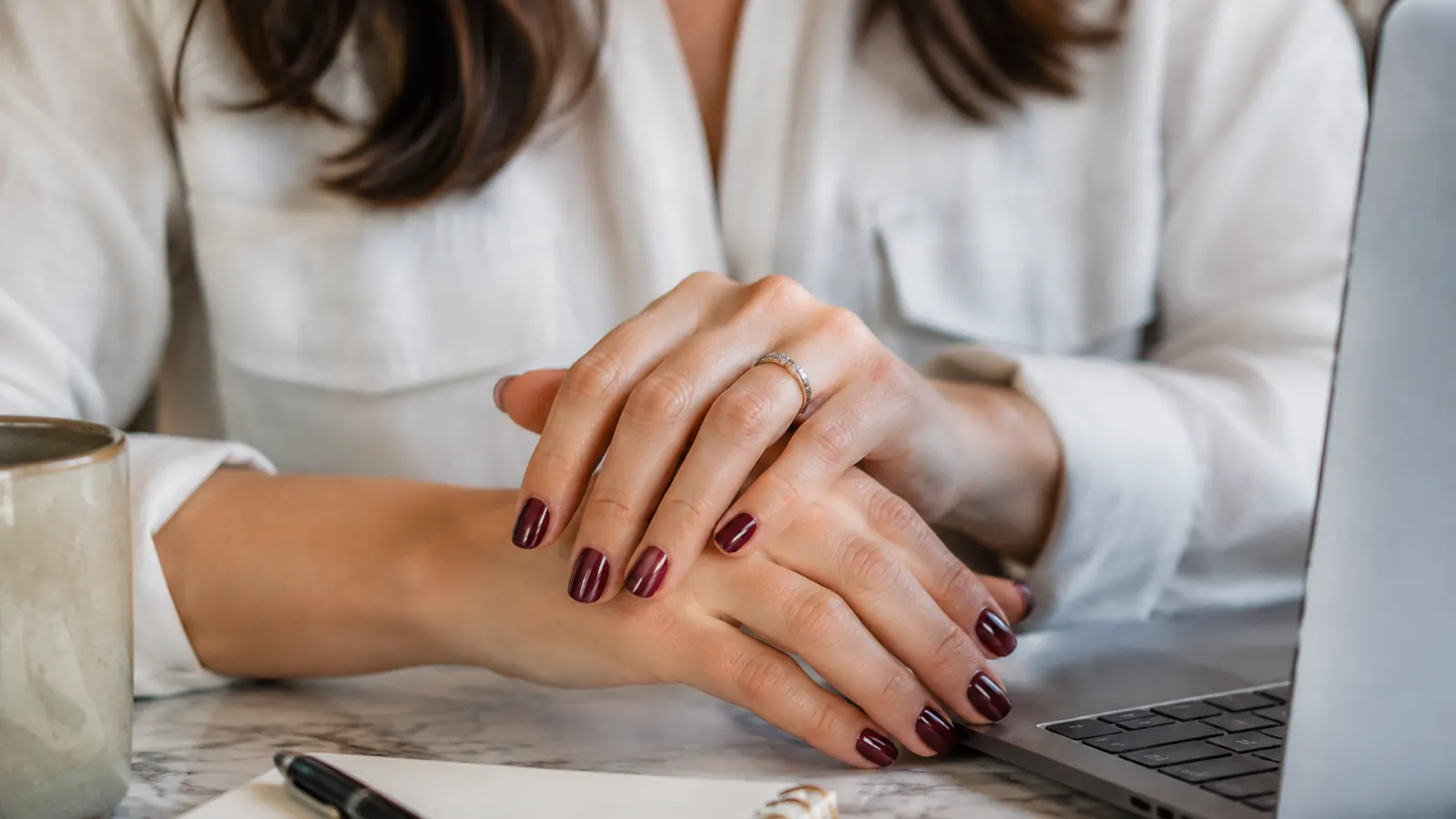 Close-up of freshly painted glossy gel nails resting on a laptop keyboard