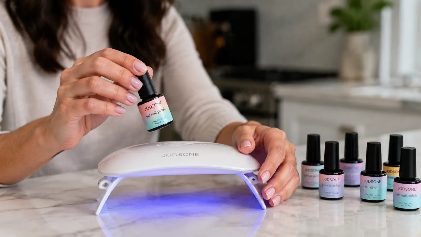 Close-up of a hand holding the JODSONE gel polish bottle over an open UV lamp